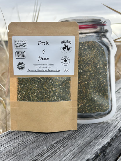 Brown kraft pouch and mason jar pouch of Maas BBQ Dock & Dine unique foodie Famous Seafood Seasoning, a salt‑free & sugar‑free 30g spice blend for seafood, labeled “Made in Canada” and “Dock & Dine” with seafood and BBQ icons.