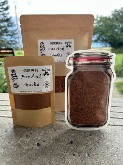 Brown kraft packaging and Mason jar of Maas BBQ “Fire And Smoke” sugar‑free famous Asian spice blend, a unique foodie BBQ seasoning labeled Asian Seasoning 50g, Made in Canada. Great for foodies, chefs an food lovers