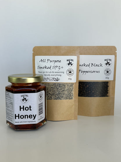 Jar of Maas BBQ hot honey and smoked black peppercorns on a white background. Made in Alberta Canada for the gourmet loving foodie