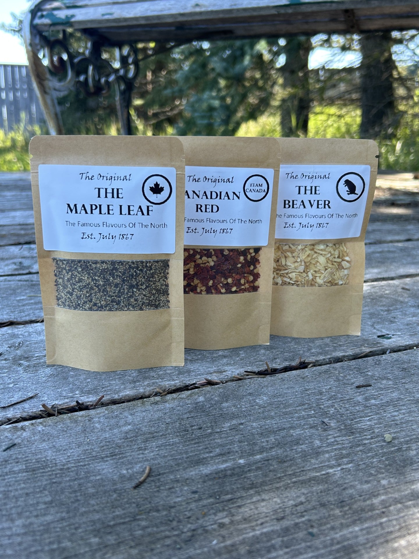 Three brown kraft bags of Maas BBQ seasoning blends made in Alberta Canada – “The Maple Leaf”, “Canadian Red”, and “The Beaver” – a unique True North foodie gift pack for cooking, BBQ recipes, and great culinary gifts.