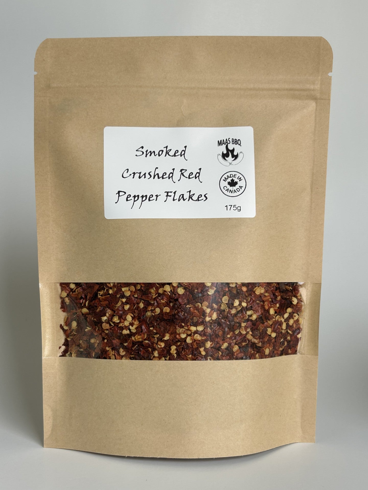 A chefs size pouch of Maas BBQ Smoked Crushed Red Pepper Flakes, showcasing the vibrant red flakes. This premium, unique smoked spice is made in Alberta, Canada, perfect for adding gourmet flavor to cooking, BBQ, and recipes for any foodie, and makes a great gift.