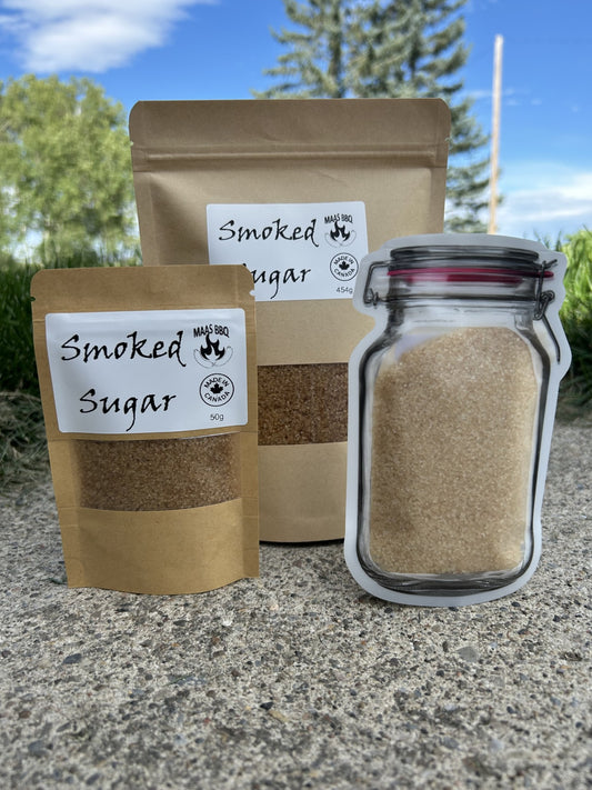 Maas BBQ Premium Smoked Sugar displayed in a 50g kraft pouch, a 454g kraft pouch, and a unique jar-shaped pouch, all against a natural outdoor background. This gourmet, unique smoked sugar is made in Alberta, Canada, perfect for adding distinct smoky-sweet flavor to cooking, BBQ recipes, desserts, and drinks. An ideal gift for any foodie or chef. Maas BBQ Premium Smoked Sugar – Canada’s Favorite Unique Gourmet Sweetener for Foodies & Chefs | Made in Alberta, Perfect for Cooking, BBQ & Gifts