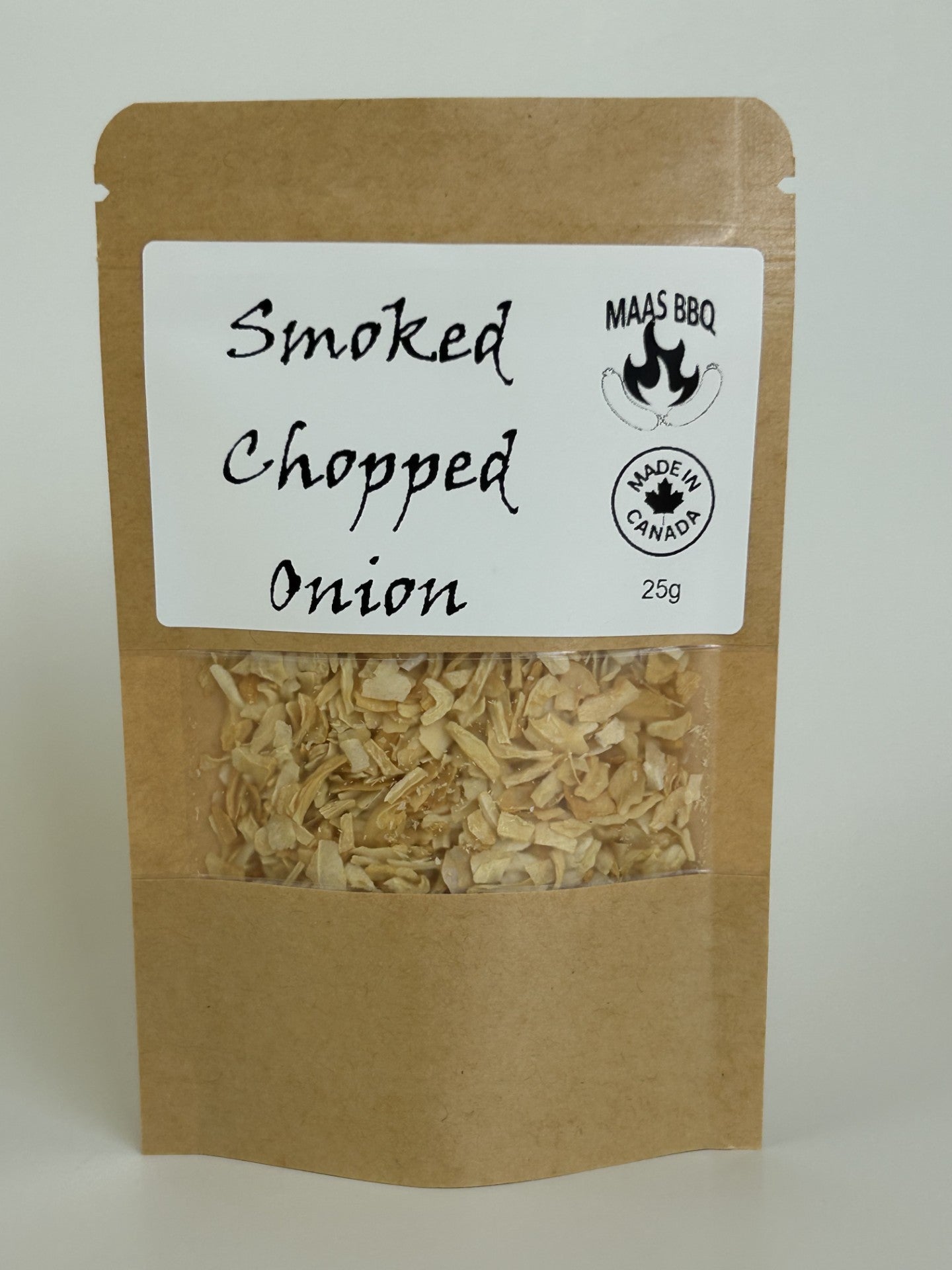 A brown resealable pouch with a white label reading “Smoked Chopped Onion” and “Maas BBQ” with a flame logo and “Made in Canada 25g” stamp; the transparent window shows dried smoked onion flakes inside.
Culinary tags: Maas BBQ, smoked onion flakes, vegan, plant‑based, gourmet, chef seasoning, BBQ flavor, onion topping, spice blend, culinary ingredient.
What to use it for: Sprinkle the smoked chopped onion flakes over salads, vegan burgers, grilled vegetables, soups, or BBQ dishes to add a rich, smoky onion 