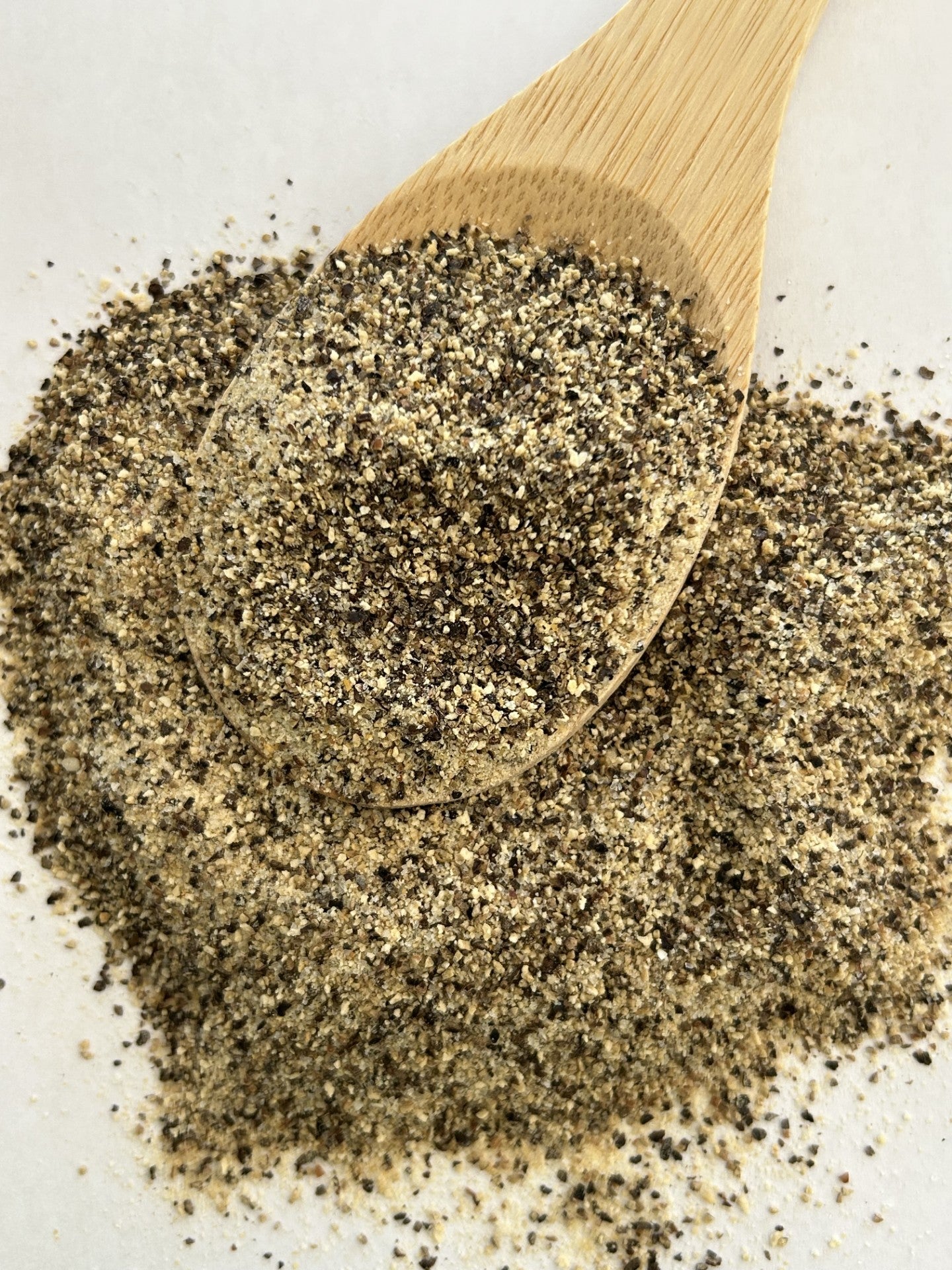Maas BBQ Smoked SPG seasoning blend, a unique Alberta Canada‑made chef spice mix for BBQ, grilling, and cooking – perfect foodie gift shown on a wooden spoon with coarse pepper and salt grains, ideal for seasoning meats, vegetables, and rubs in gourmet cooking.