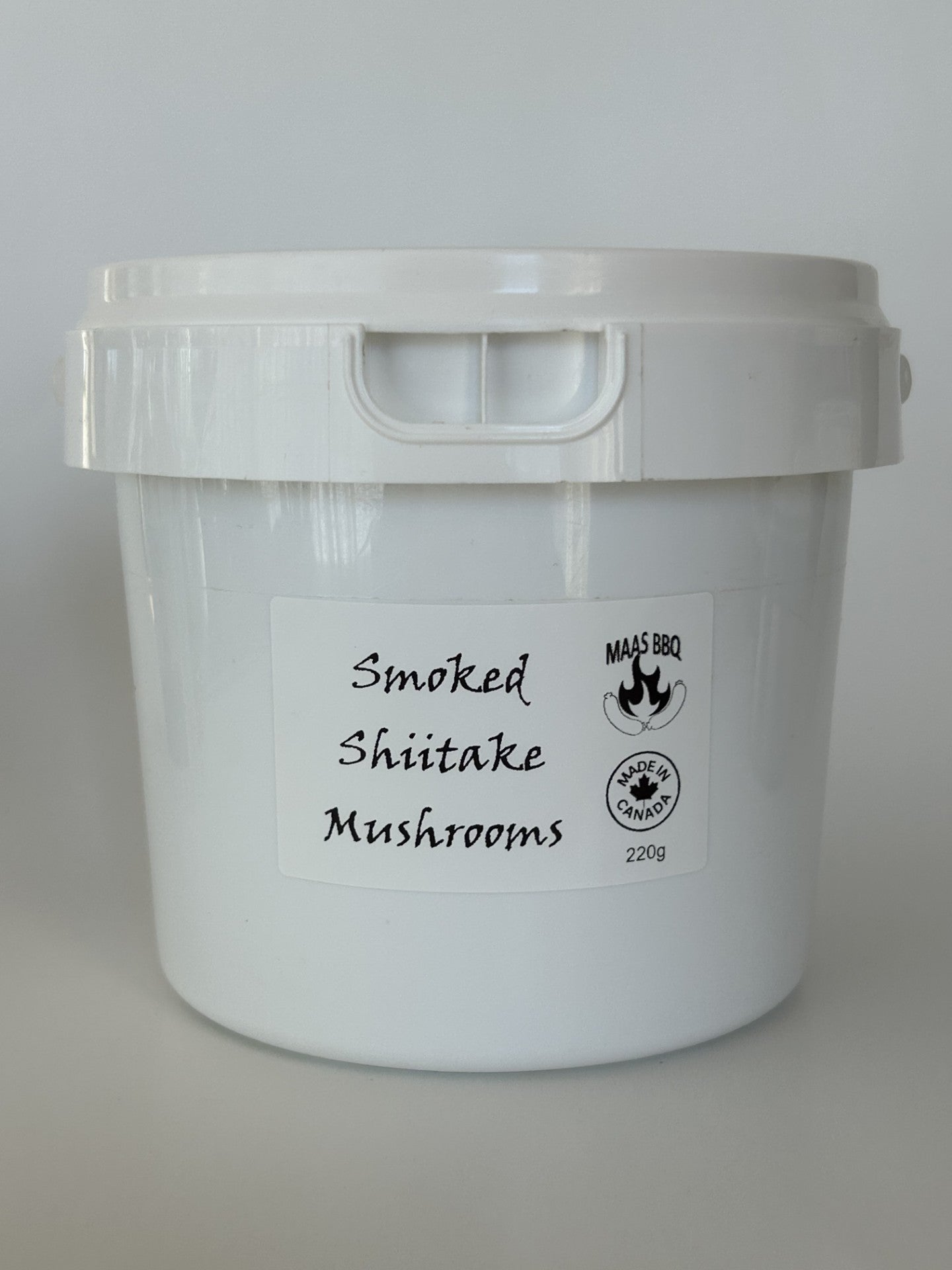 A 220g white bucket of Maas BBQ Smoked Shiitake Mushrooms, featuring the "Made in Canada" logo. This high‑end, unique gourmet ingredient, crafted in Alberta, Canada, is perfect for chefs and foodies to infuse dishes with rich, smoky umami flavors, and makes an excellent executive gift for culinary enthusiasts.