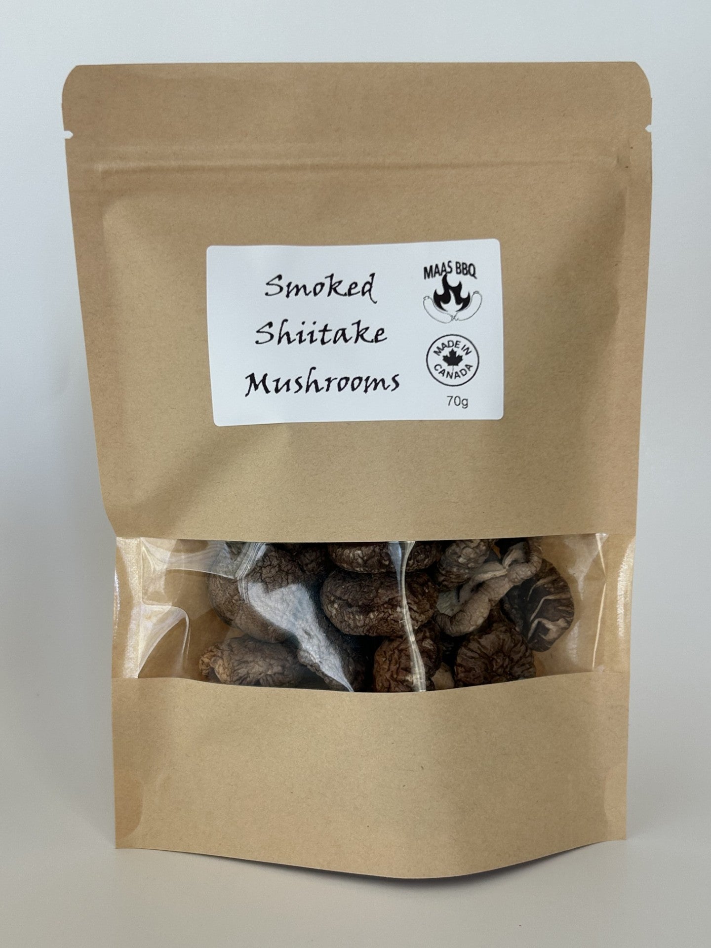 An 70g kraft pouch of Maas BBQ Smoked Shiitake Mushrooms, featuring the "Made in Canada" logo. These high‑end, unique gourmet smoked shiitake mushrooms, crafted in Alberta, Canada, are perfect for chefs and foodies to infuse dishes with rich, smoky umami flavors, and make an excellent gift for culinary enthusiasts.