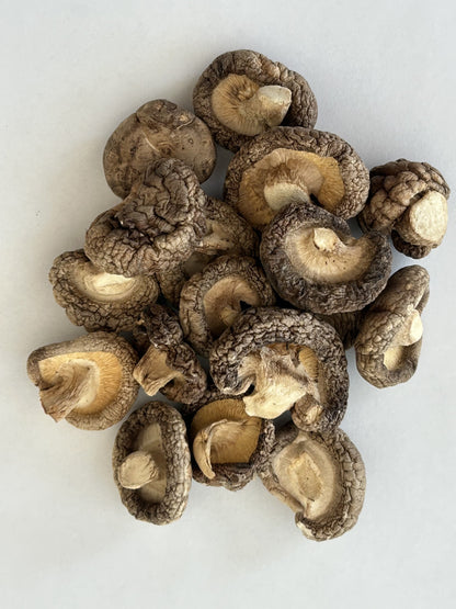 A close‑up pile of Maas BBQ Smoked Shiitake Mushrooms on a white background, showcasing their unique texture and rich, smoky color. These high‑end, gourmet smoked mushrooms, crafted in Alberta, Canada, are perfect for chefs and foodies to infuse dishes with rich, smoky umami flavors in cooking, and make an excellent executive gift.