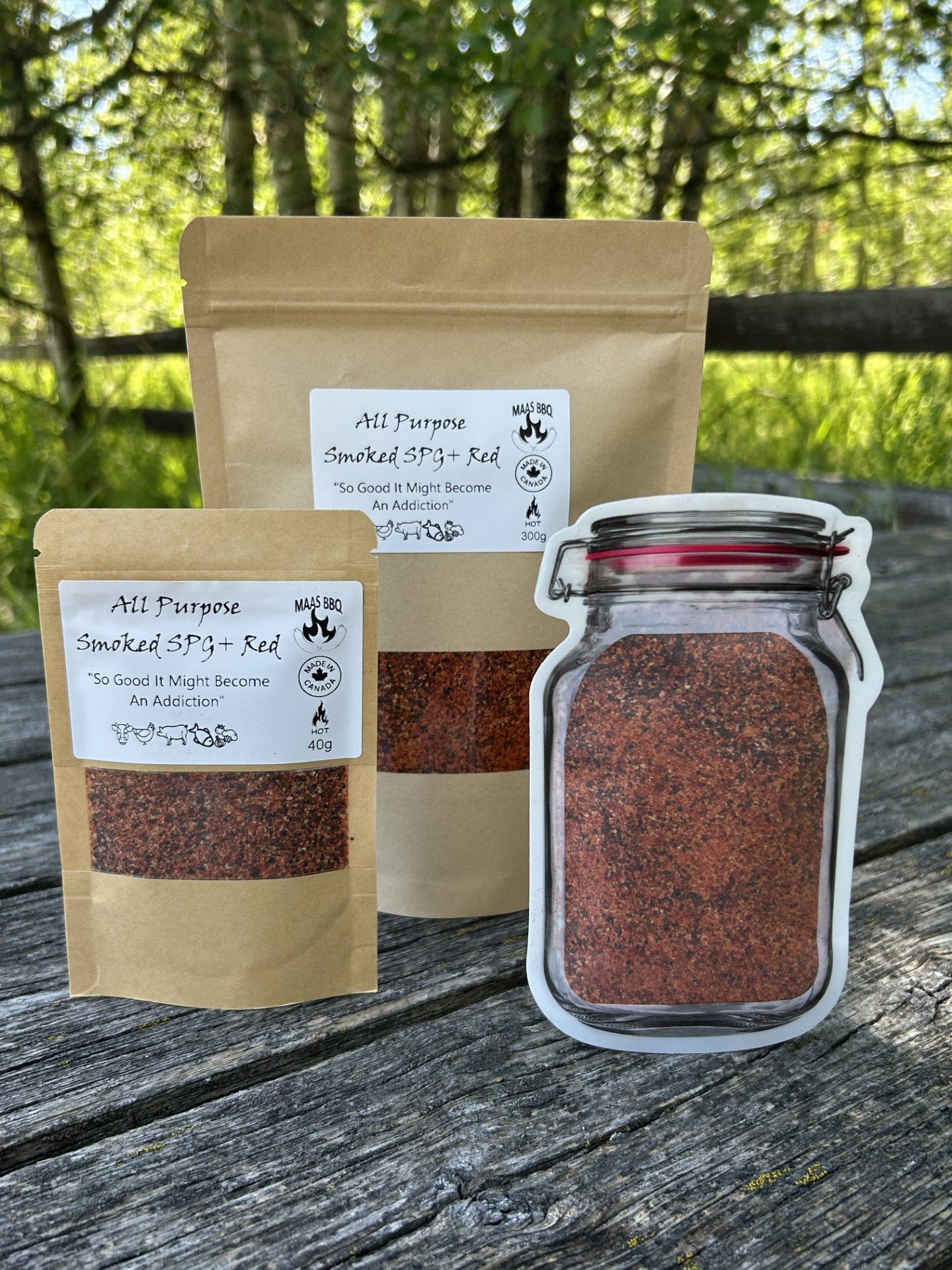 Maas BBQ Spicy All Purpose Smoked SPG+ seasoning displayed in unique mason jar re-sealable pouches and traditional 45g bags. Features include a close-up of coarse spice texture, popcorn seasoning application, and grilled salmon.