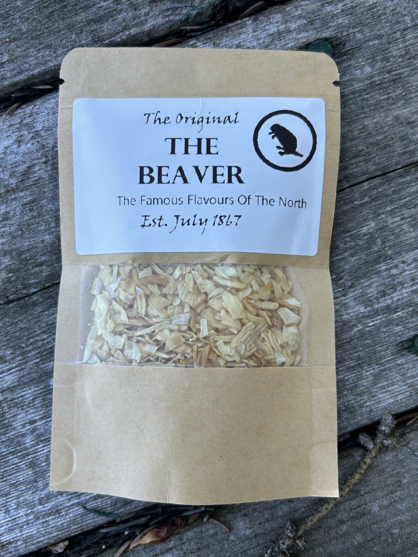 Brown kraft pouch with clear window showing smoked onion flakes, labeled “The Original THE BEAVER – The Famous Flavours Of The North, Est. July 1867,” a unique Maas BBQ foodie gift made in Alberta Canada for cooking, BBQ recipes, and great gift ideas – True North onion flake seasoning.
