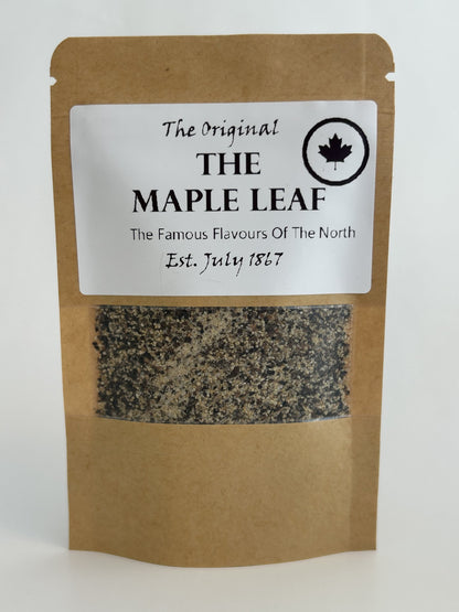Brown kraft pouch of unique Maple Leaf smoked SPG seasoning labeled “The Original THE MAPLE LEAF – The Famous Flavours Of The North, Est. July 1867,” a great foodie gift made in Alberta Canada for Maas BBQ cooking and recipe inspiration. A great gift for food loving lumberjacks. 