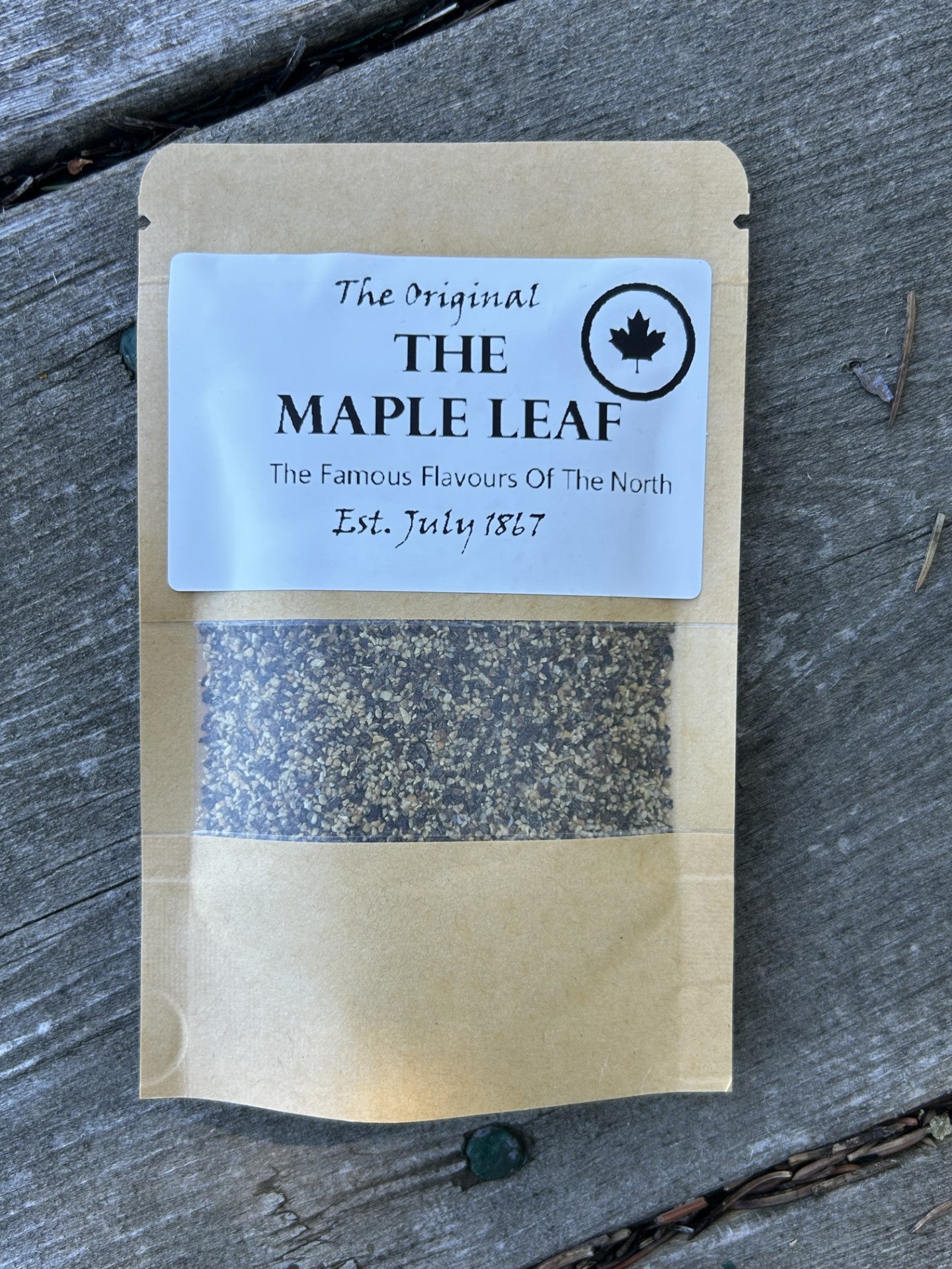 Brown kraft pouch of unique Maple Leaf smoked SPG seasoning labeled “The Original THE MAPLE LEAF – The Famous Flavours Of The North, Est. July 1867,” a great foodie gift made in Alberta Canada for Maas BBQ cooking and recipe inspiration.